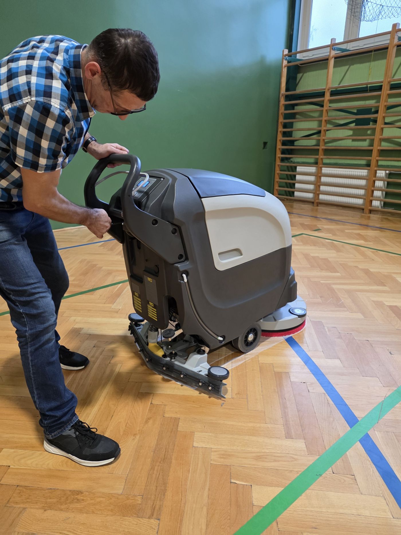 Operator prowadzi szorowarkę Fabula 50 BT po parkiecie sali gimnastycznej