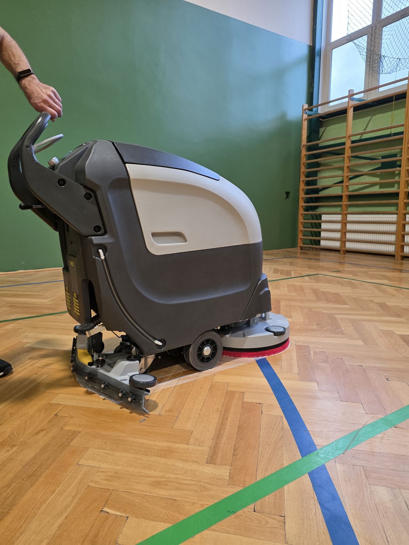 Szorowarka Fabula 50 BT na parkiecie sali gimnastycznej — widok z boku z opuszczoną głowicą