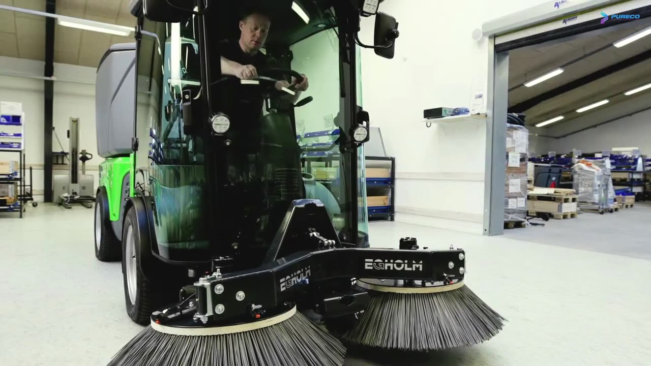 Operator w kabinie City Rangera 3070 z zamiatarką w hali serwisowej — skala maszyny