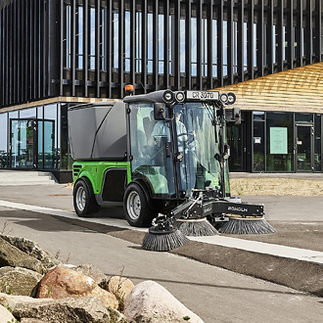 Egholm City Ranger 3070 z zamiatarką pracuje wolno wzdłuż budynku