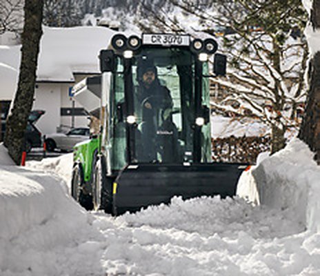 Egholm City Ranger 3070 z pługiem odgarnia śnieg z ulicy między zaspami